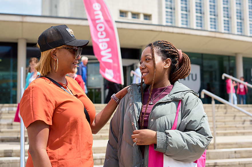 Prospective student and her mum standing outside of NTU's Newton building and chatting