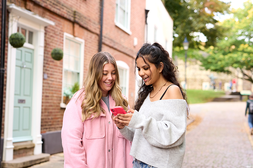 Two students looking at a phone and smiling