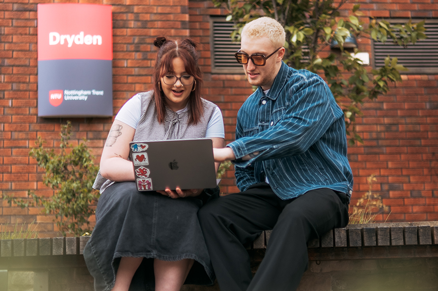 Students looking at a laptop together outside NTU's Dryden building