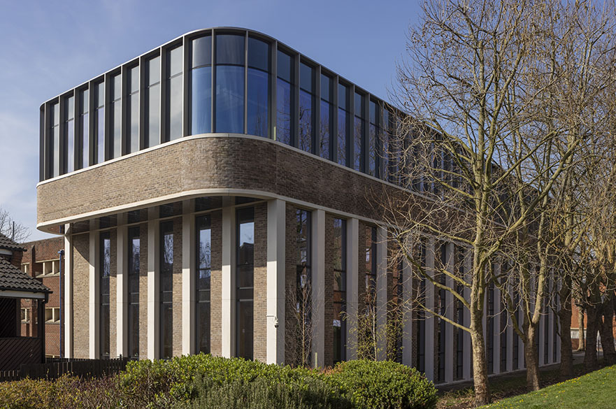 An image of the curving Dryden Enterprise Centre in the sun, surrounded by bushes and trees.