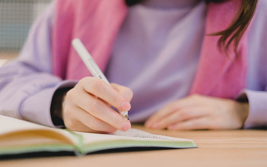 A hand writing in a note book