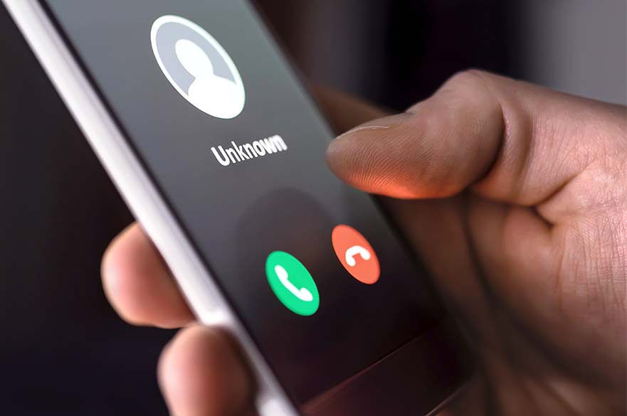 Person holding phone in hand, with called ID showing as unknown