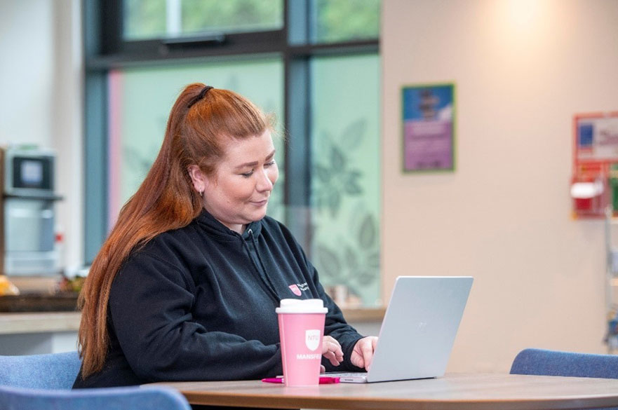 A female student sitting at a desk with a laptop open in front of her