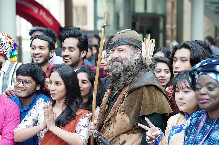 A group of people from different cultures stand around Robin Hood